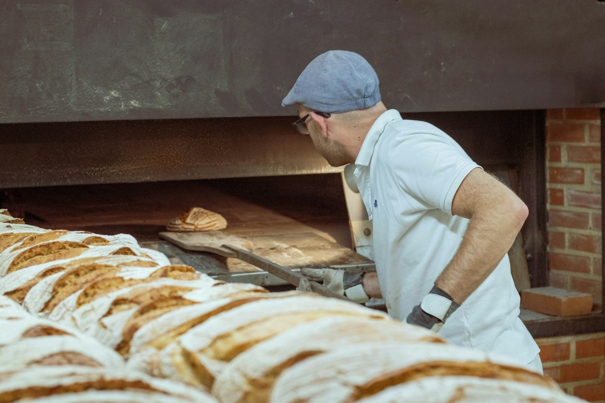 A baker loading loaves into a wood-fired oven