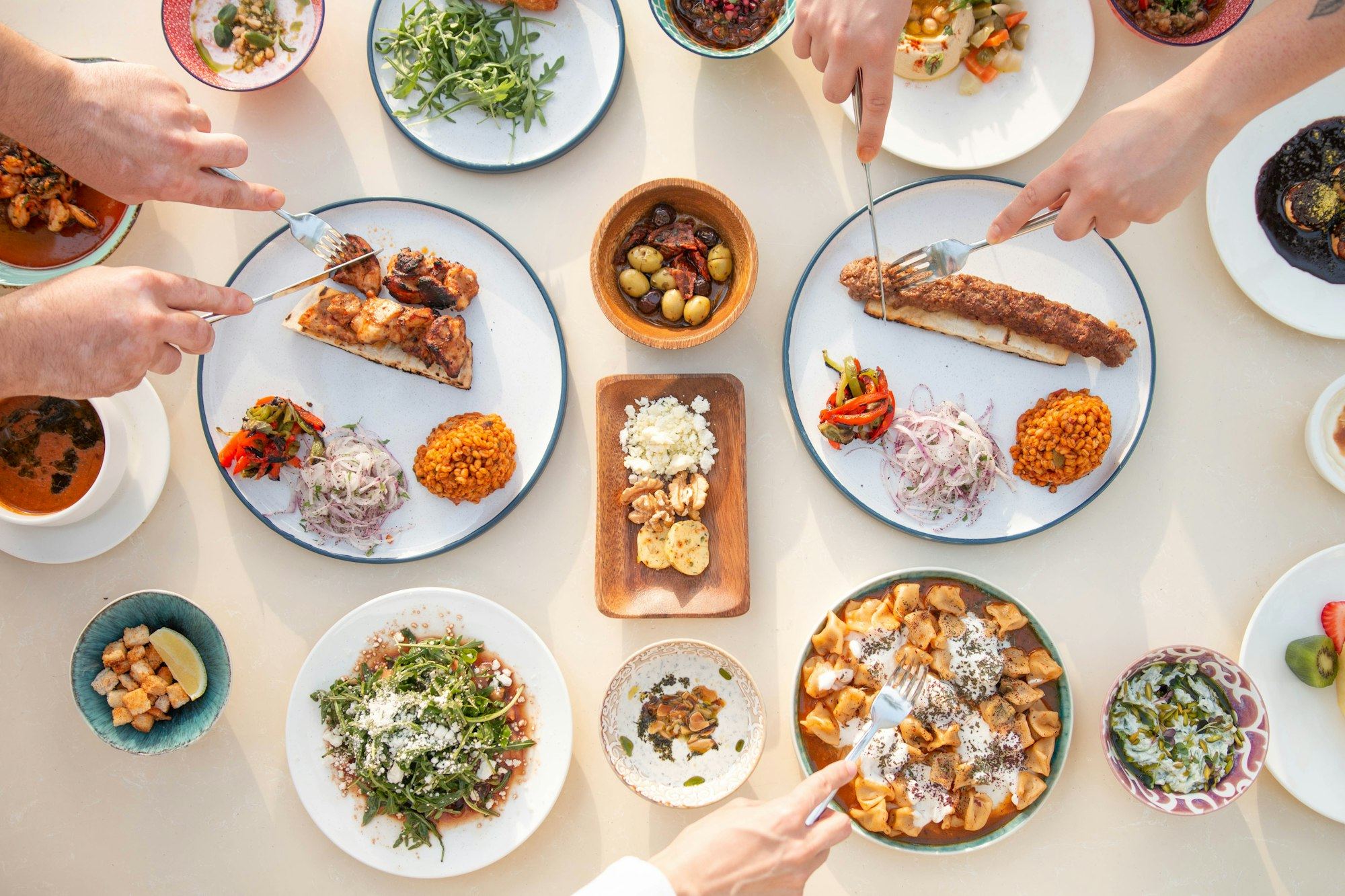 A shared lunch table seen from above, with grilled dishes, salads and dips