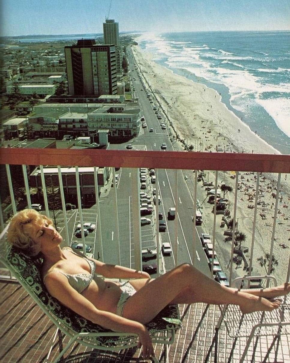 A vintage photo: a sunbather on a high-rise balcony above the beach, the surf and the Esplanade