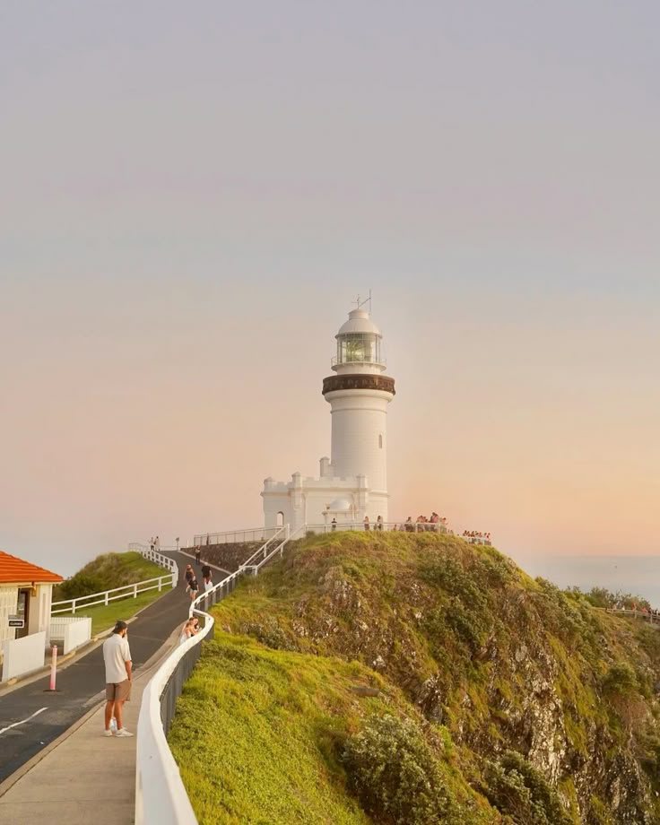 Cape Byron Lighthouse at sunset, with walkers on the path up the headland