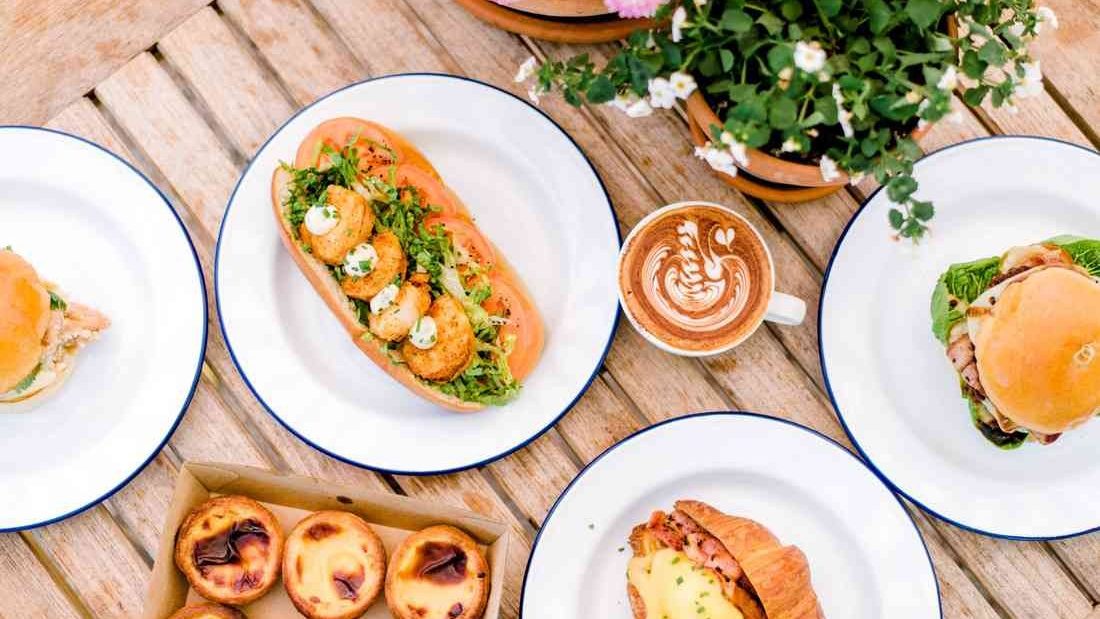 Brunch plates, pastries and a latte on a table at Custard Canteen