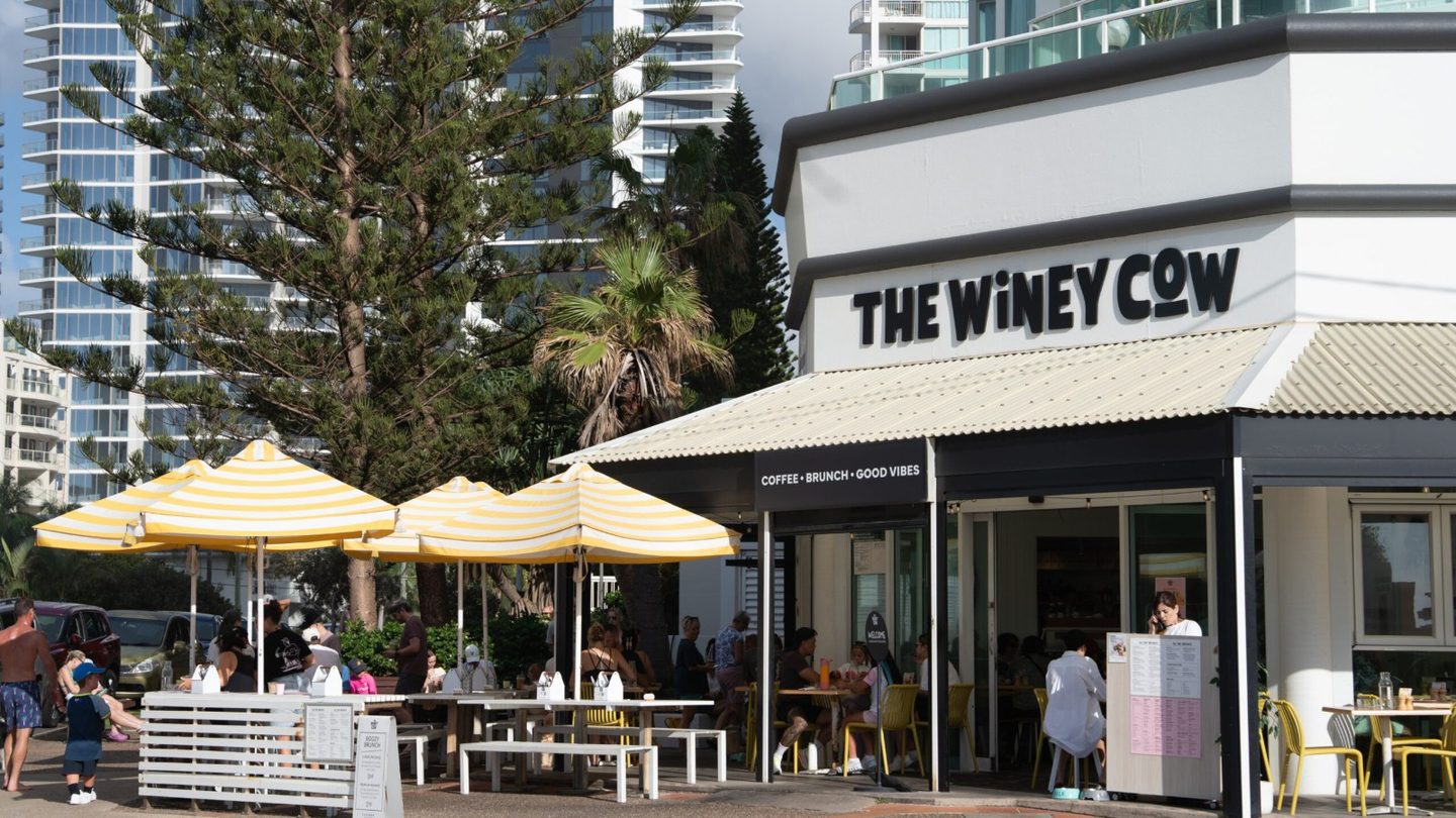 The Winey Cow at Main Beach, with yellow umbrellas over the outdoor tables