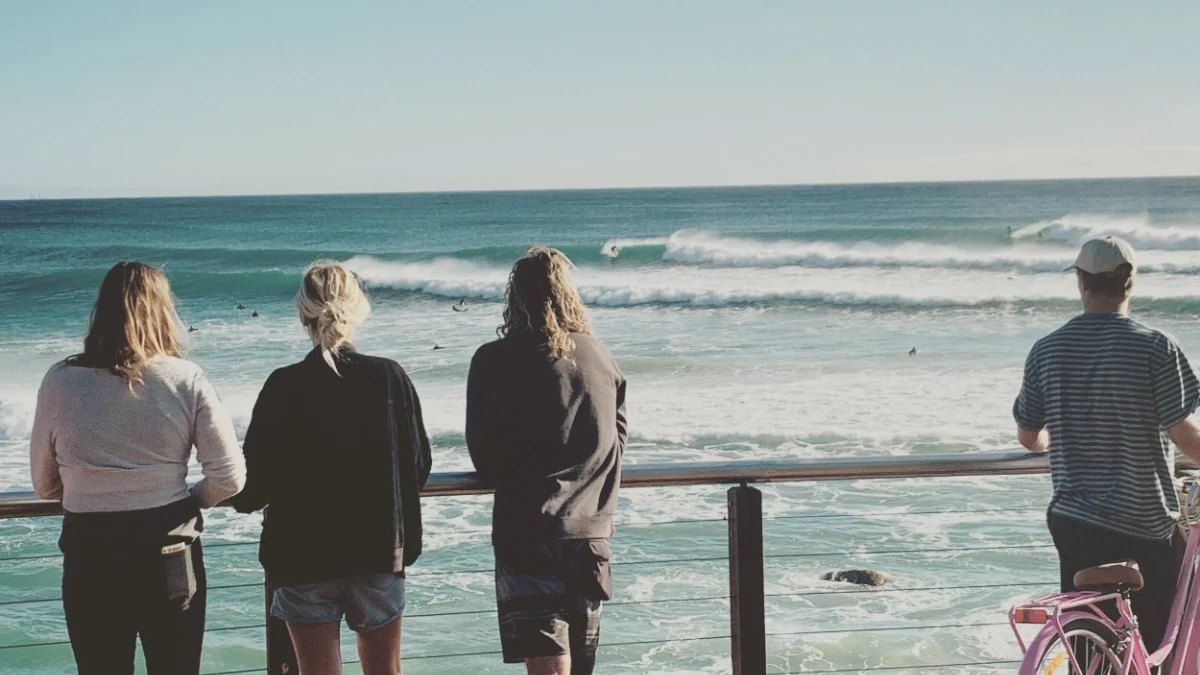 People leaning on a rail, watching the surf