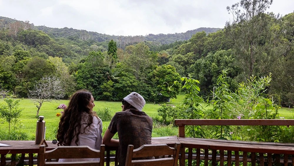 Two people at the rail at Currumbin Valley Harvest, looking over the green valley