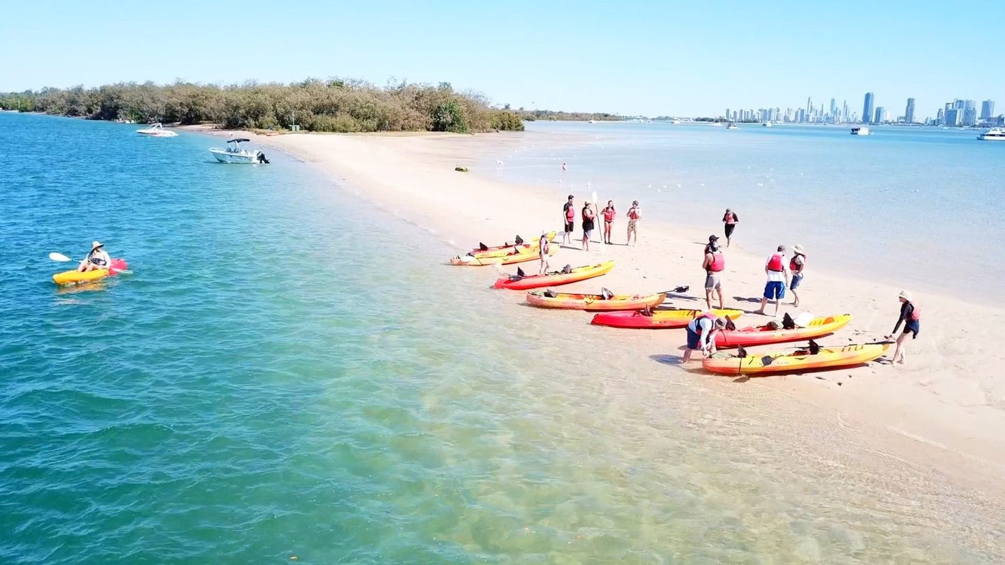 Kayaks on the beach at Wave Break Island, with Surfers Paradise in the distance