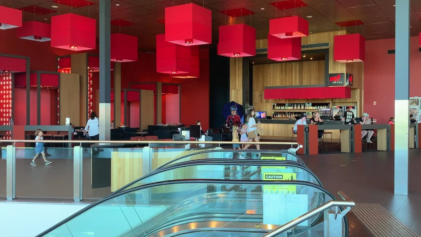 The red-lit foyer and escalator at Event Cinemas Robina