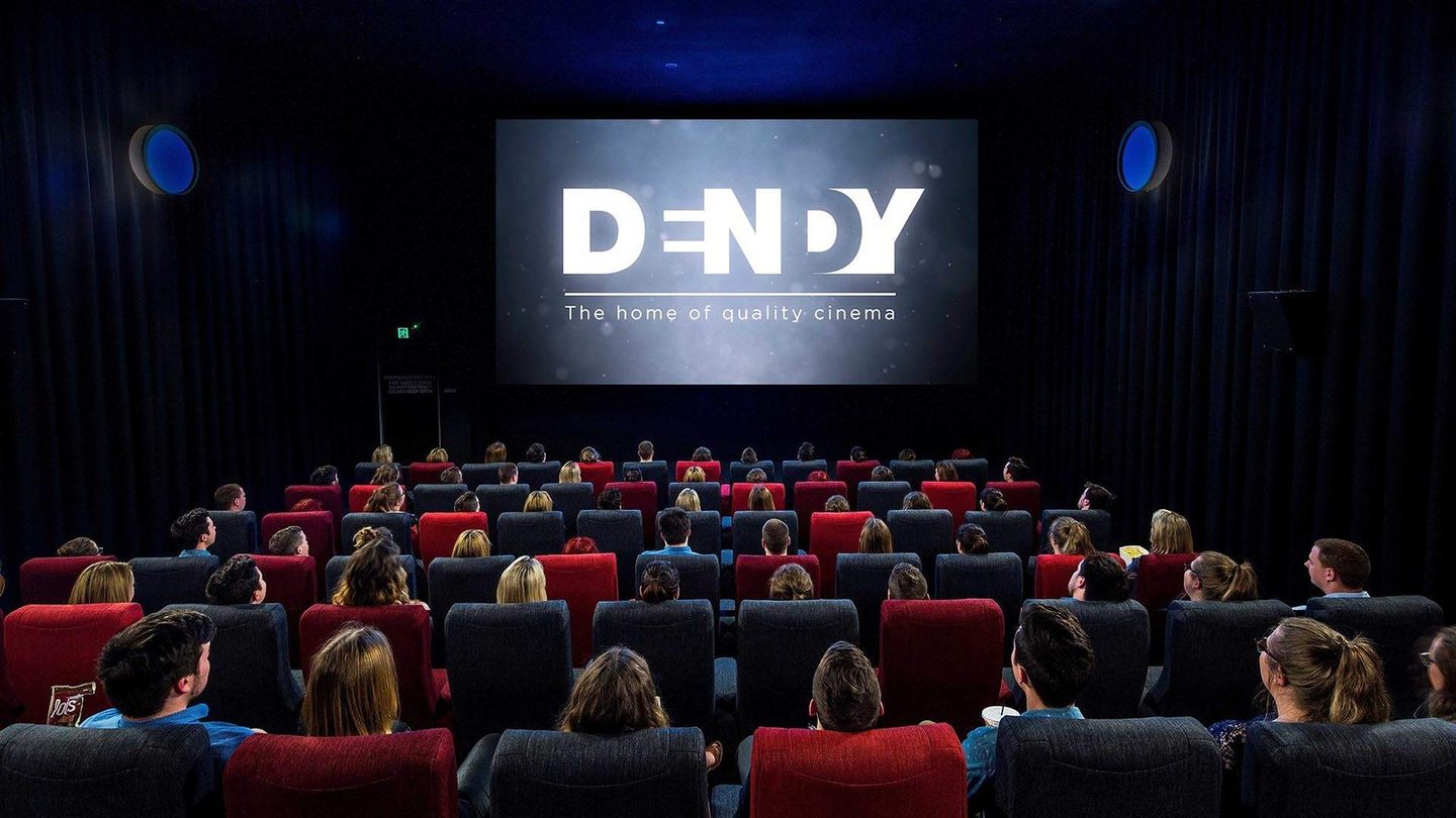 An audience in the red seats at Dendy Southport, with the Dendy logo on screen