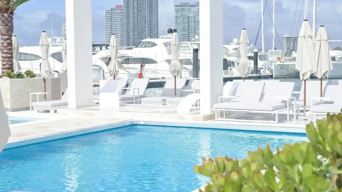 The pool and sun lounges at La Luna Beach Club, with boats in the marina