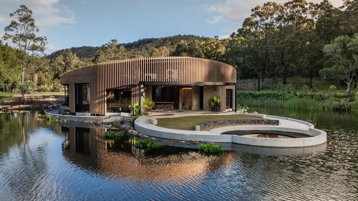 The curved timber Sol Elements bathhouse beside its pond