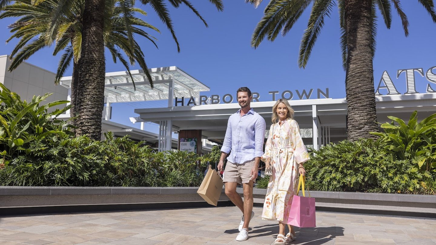 Shoppers walking past the Harbour Town sign and palms