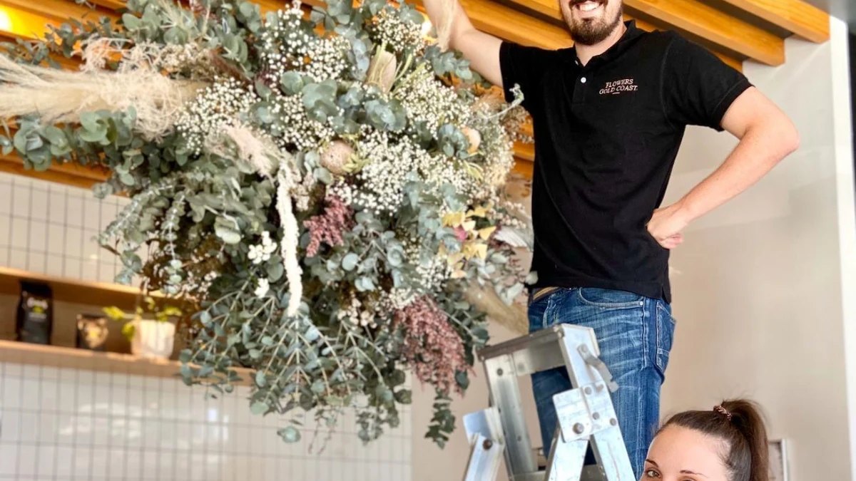 A florist hanging a dried-flower installation at Flowers Gold Coast