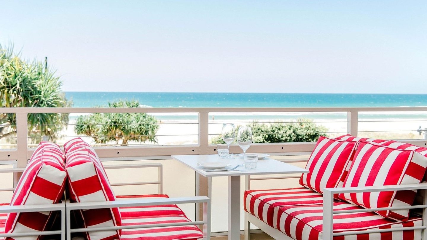 Red-and-white striped lounges on Tommy's Italian balcony above the beach