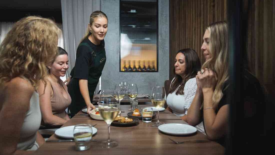 Friends being served at a table at Social Eating House + Bar