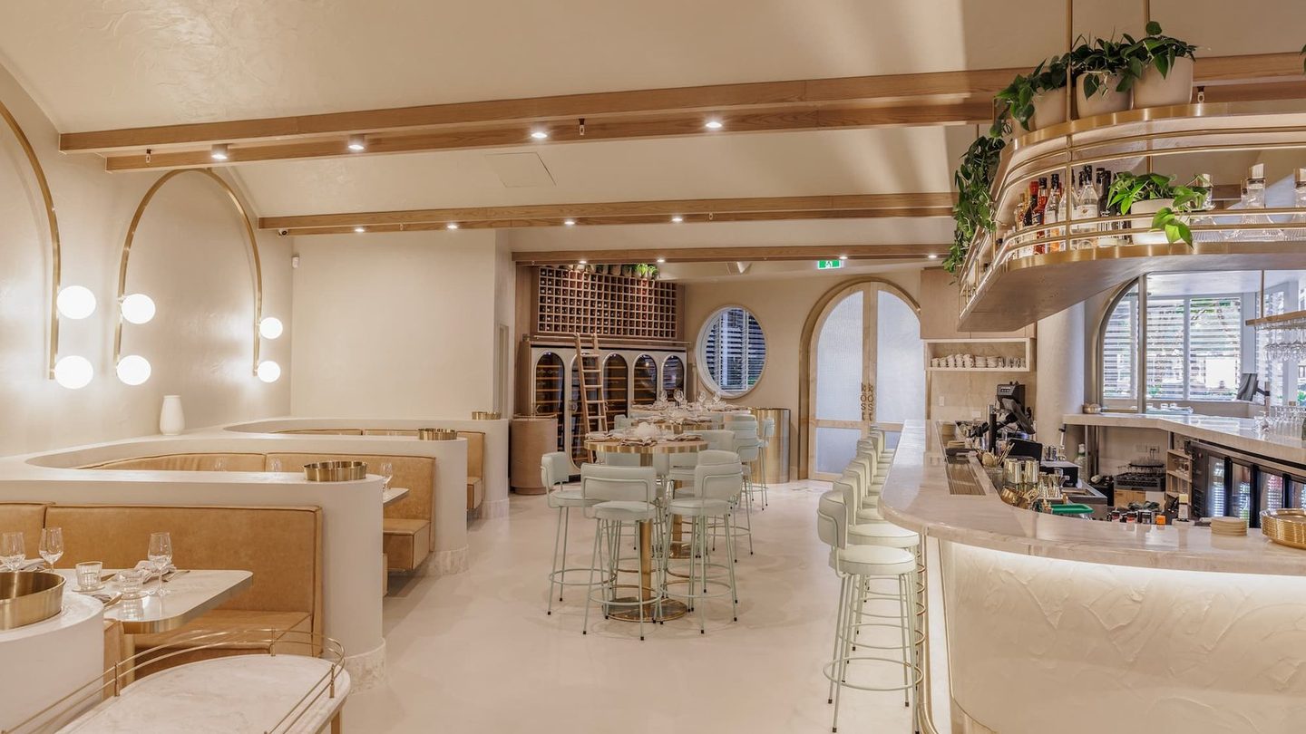 The bright dining room at Kōst Bar & Grill, with arched windows and booths