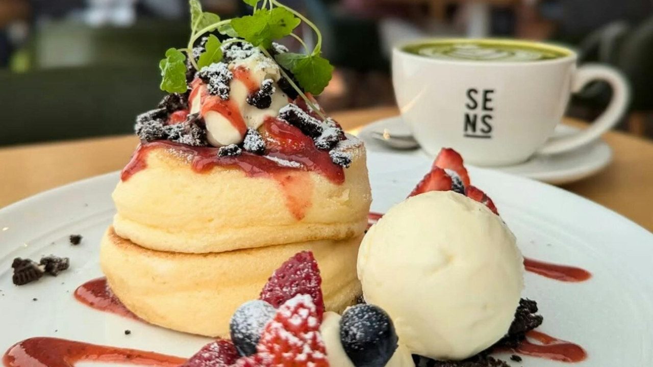 Soufflé pancakes with berries beside a Sens Fusion cup