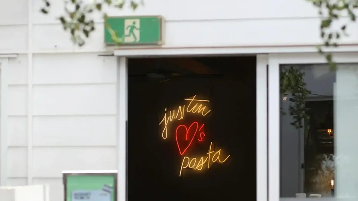 The 'Justin loves pasta' neon sign in the doorway at Justin Lane