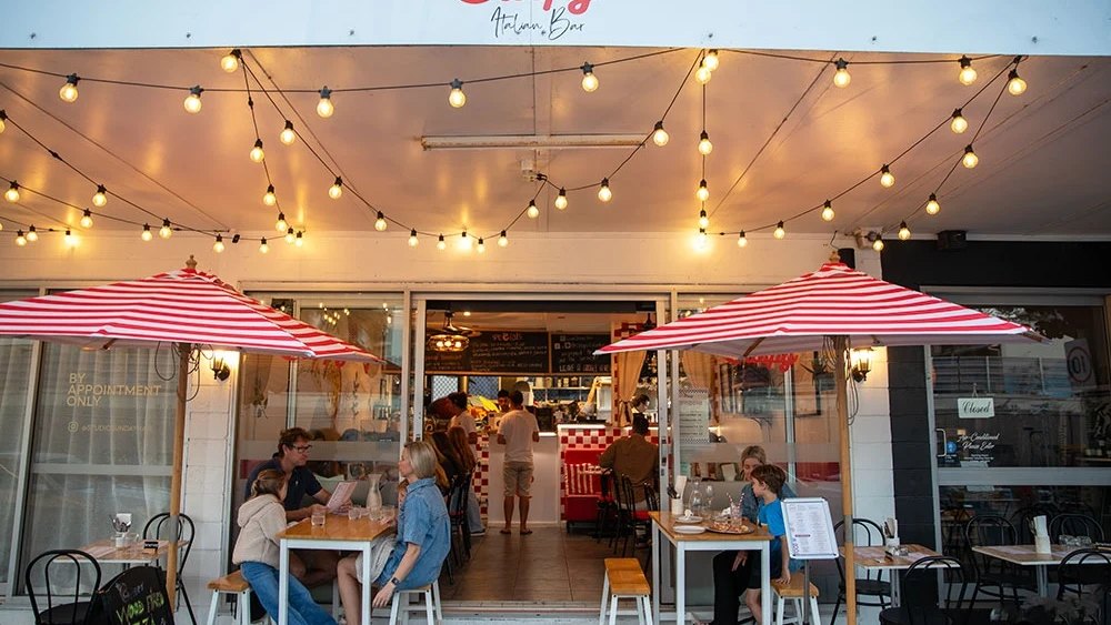 Striped umbrellas and festoon lights over the tables outside Crispy Italian Bar