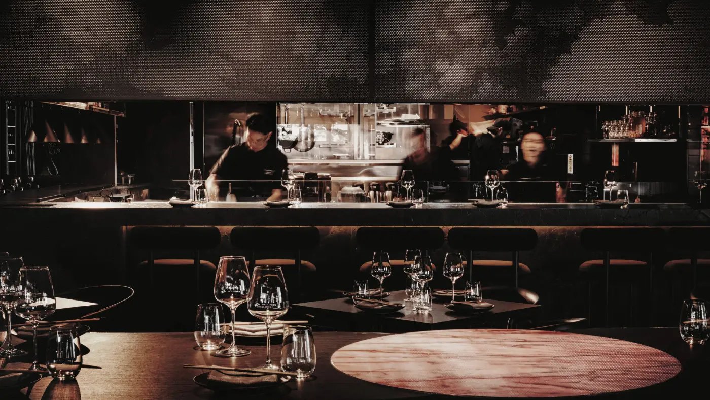The dark dining room at Mamasan, with chefs at the open kitchen behind