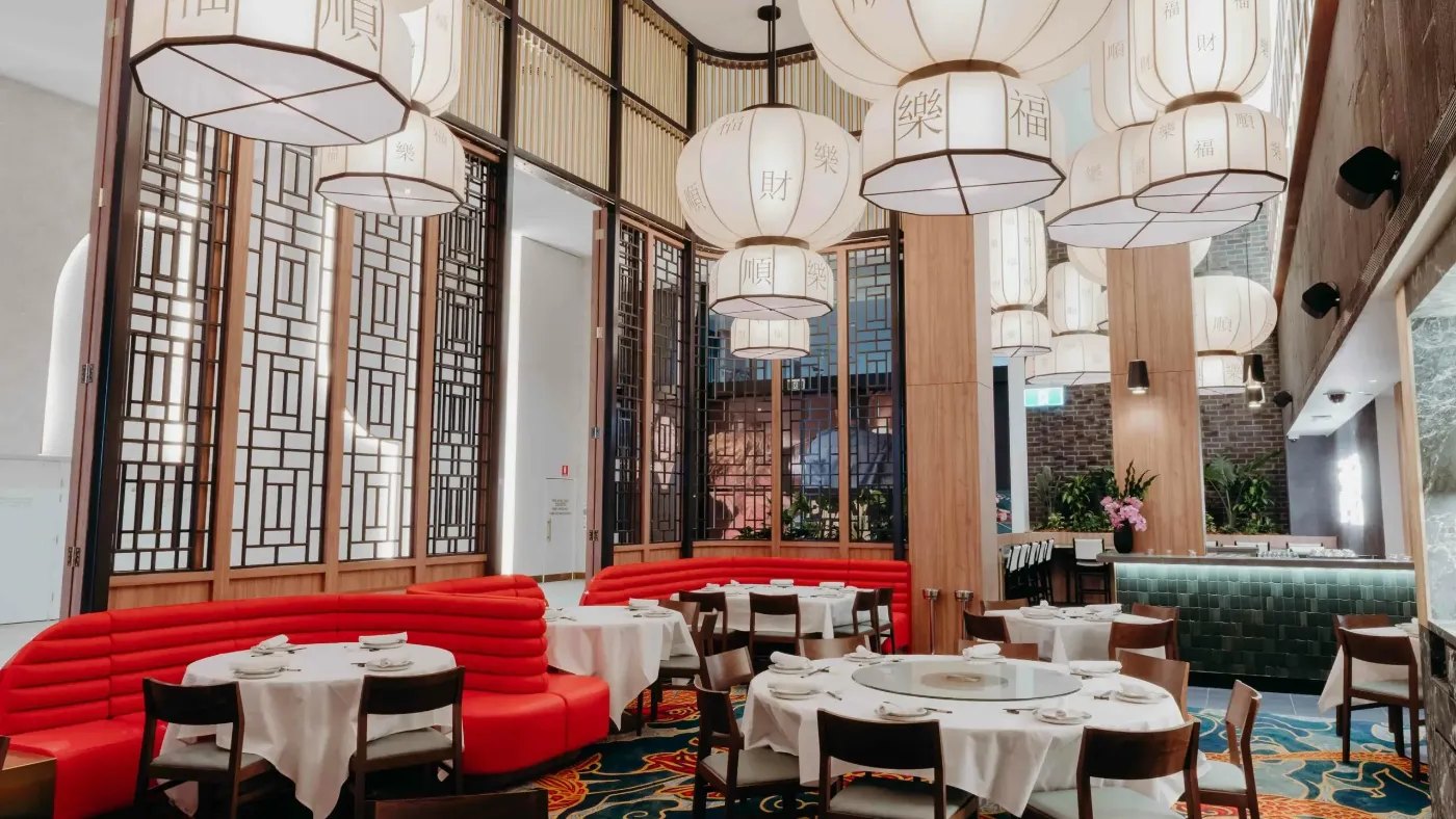 Red banquettes and white tablecloths under paper lanterns at Uncle Su