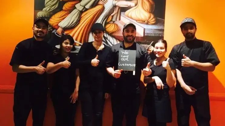 The Temple of Spices team in front of the restaurant mural