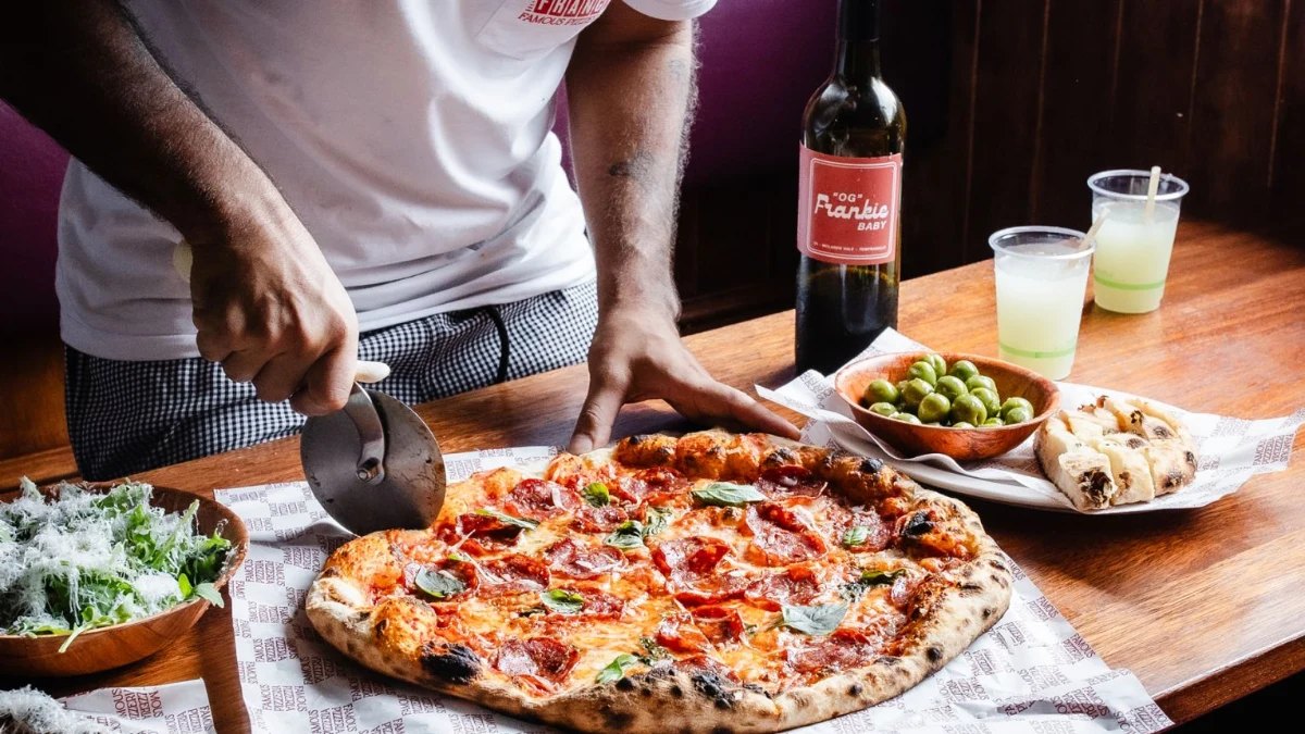 A pepperoni pizza being sliced at Franc Jrs