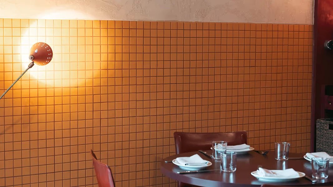An orange tiled wall and a table set for dinner at Bar Monte