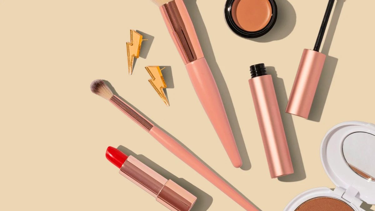 Make-up and brushes laid out on a beige background