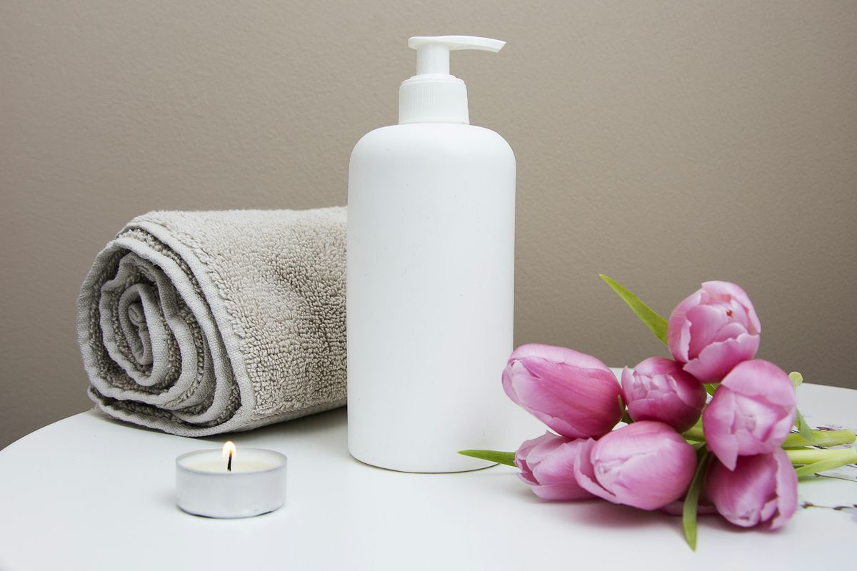 A pump bottle, a rolled towel and pink tulips